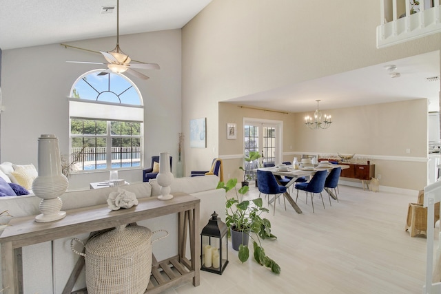 living room with a high ceiling and ceiling fan with notable chandelier