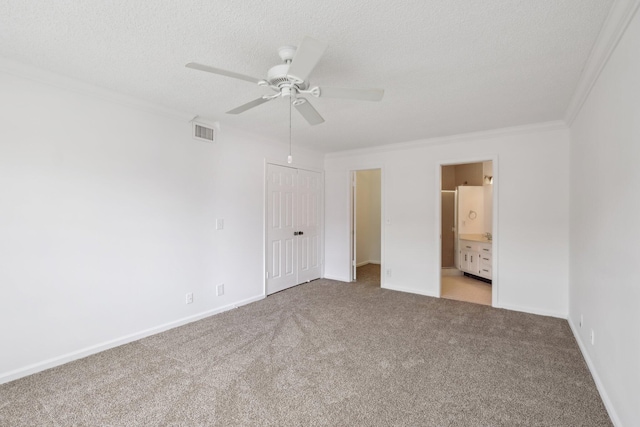 unfurnished bedroom with ceiling fan, light colored carpet, ensuite bath, ornamental molding, and a closet