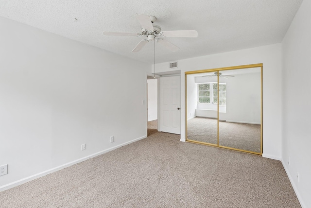 unfurnished bedroom featuring carpet floors, a closet, a textured ceiling, and ceiling fan