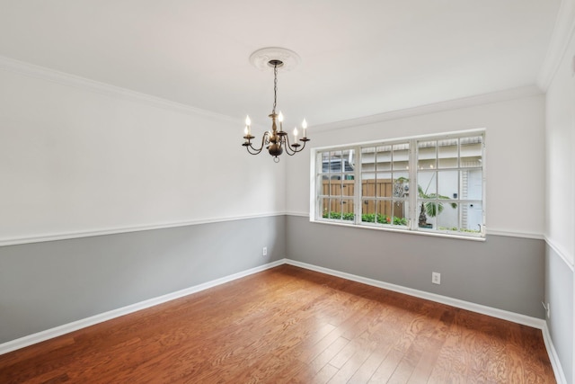 unfurnished room with wood-type flooring, ornamental molding, and a notable chandelier