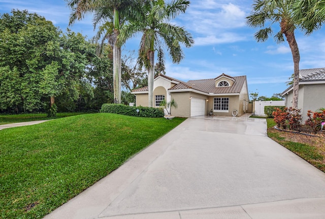 mediterranean / spanish home with stucco siding, a front lawn, a gate, a tile roof, and concrete driveway