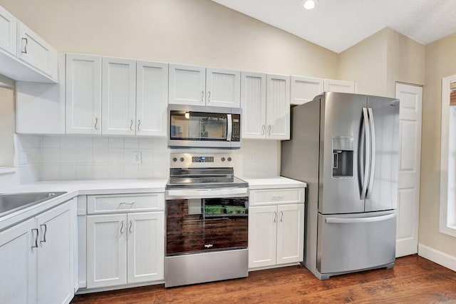 kitchen featuring appliances with stainless steel finishes, dark wood-style floors, vaulted ceiling, and light countertops