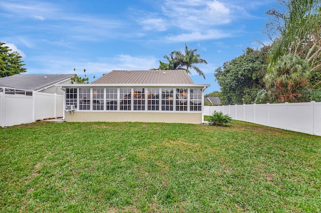 rear view of property with a lawn and a sunroom