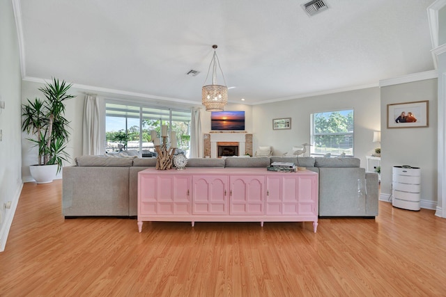 living room with light wood-type flooring, crown molding, and a healthy amount of sunlight