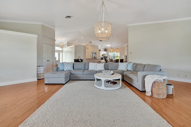 living room with vaulted ceiling, light wood-type flooring, a notable chandelier, a healthy amount of sunlight, and ornamental molding