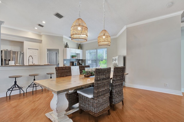 dining room with sink, ornamental molding, and light hardwood / wood-style flooring