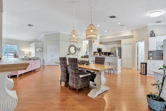 dining space with sink, light wood-type flooring, and crown molding