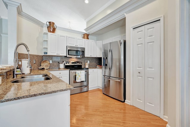 kitchen with sink, stainless steel appliances, white cabinets, and kitchen peninsula