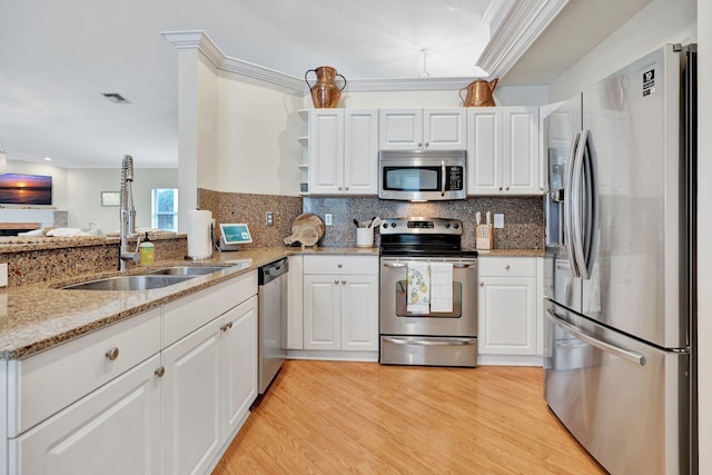 kitchen with white cabinets, decorative backsplash, light wood-type flooring, and appliances with stainless steel finishes