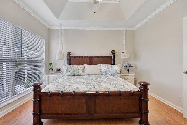 bedroom with light hardwood / wood-style floors, a tray ceiling, and crown molding