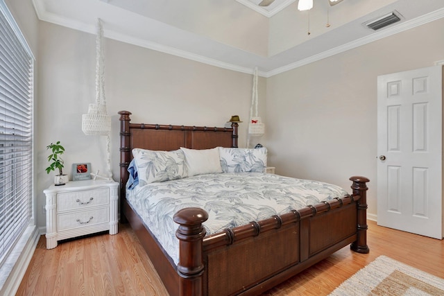 bedroom featuring ceiling fan, crown molding, light hardwood / wood-style flooring, and multiple windows