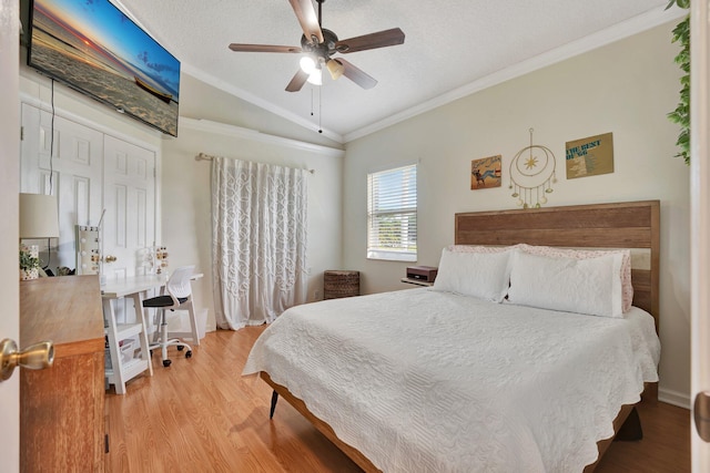 bedroom featuring vaulted ceiling, a closet, light wood-type flooring, crown molding, and ceiling fan