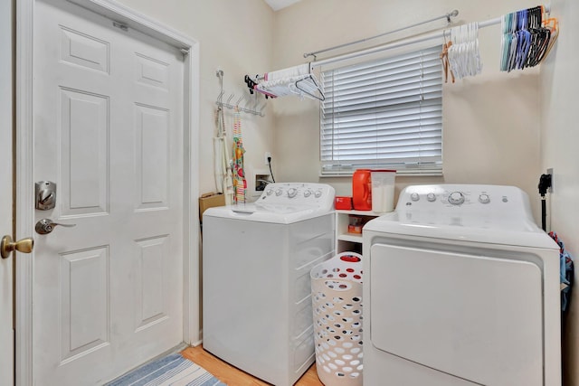 clothes washing area with separate washer and dryer and light hardwood / wood-style floors