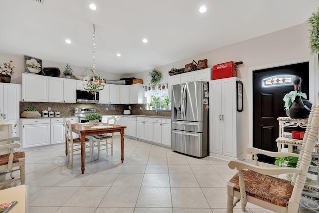 kitchen with stainless steel appliances, light tile patterned floors, white cabinets, and tasteful backsplash