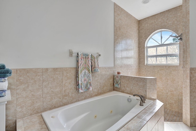 bathroom with a relaxing tiled tub, tile patterned flooring, and tile walls