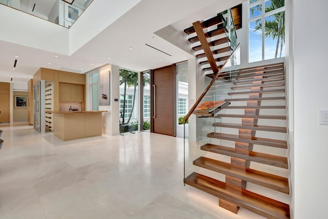 staircase featuring floor to ceiling windows and a high ceiling