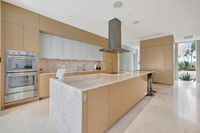 kitchen with stainless steel double oven, island exhaust hood, black electric stovetop, and a large island