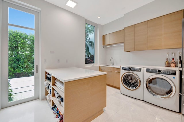 laundry room featuring washing machine and dryer, cabinets, and sink