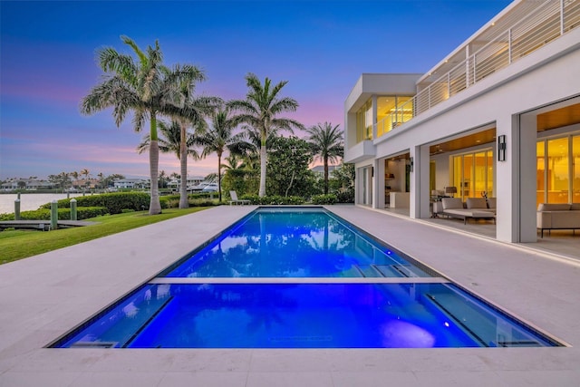 pool at dusk with an in ground hot tub and a patio