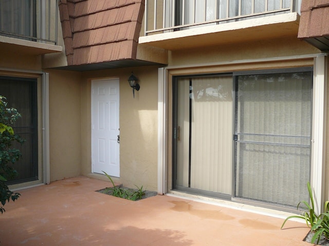 property entrance featuring a balcony and a patio