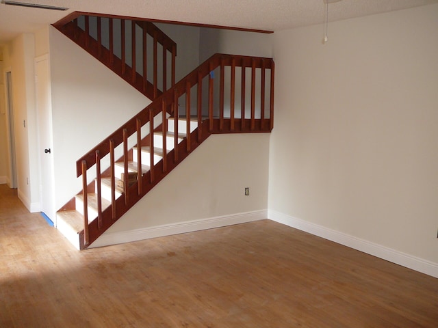 stairway with hardwood / wood-style floors and a textured ceiling