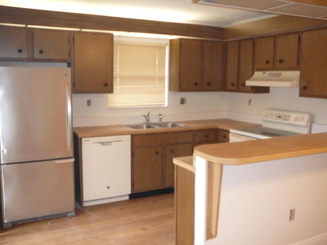 kitchen featuring kitchen peninsula, sink, electric stove, dishwasher, and stainless steel refrigerator