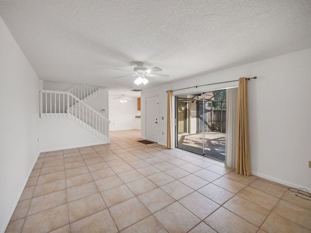 tiled empty room featuring ceiling fan and a textured ceiling