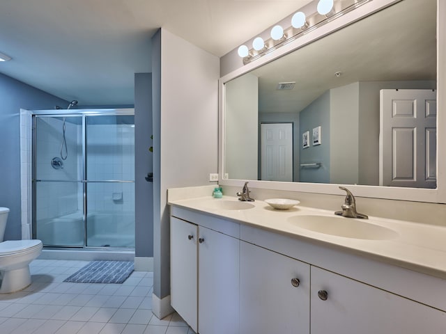 bathroom with toilet, vanity, tile patterned floors, and a shower with door