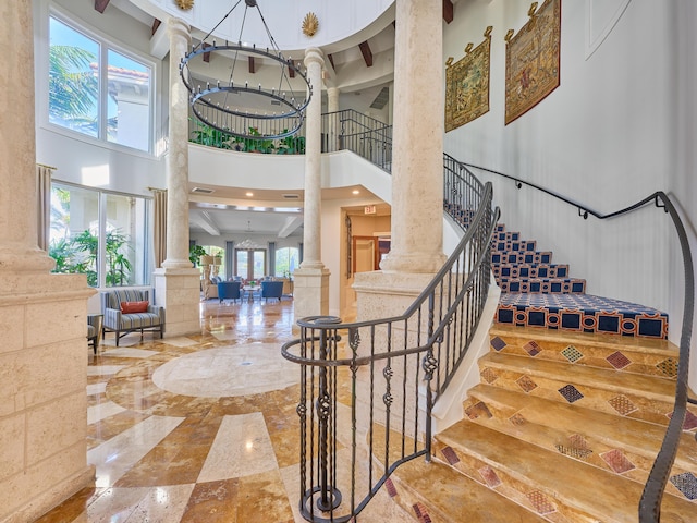 stairway featuring ornate columns and a towering ceiling