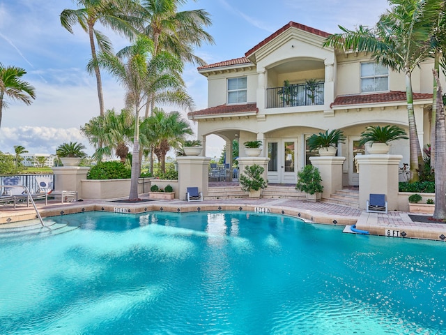 back of property with a patio, a balcony, and a community pool