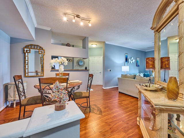 dining area with hardwood / wood-style floors, a textured ceiling, and ornamental molding