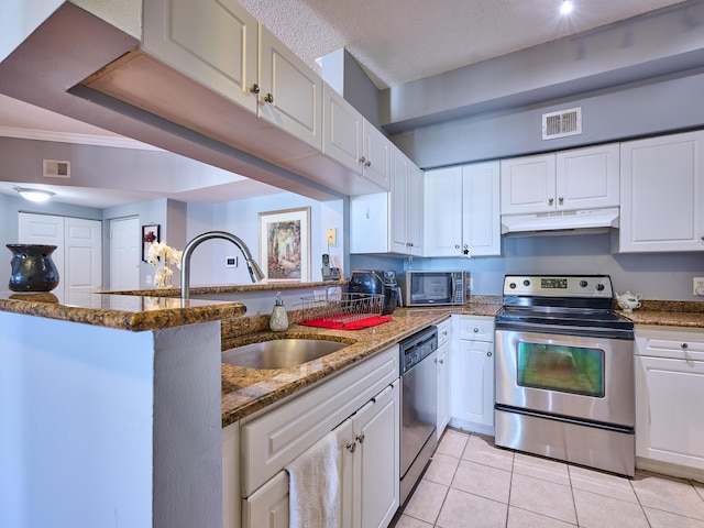 kitchen featuring kitchen peninsula, white cabinetry, dark stone countertops, and appliances with stainless steel finishes