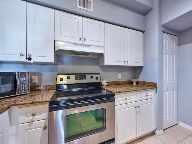 kitchen with dark stone counters, white cabinets, light tile patterned flooring, and stainless steel range with electric stovetop