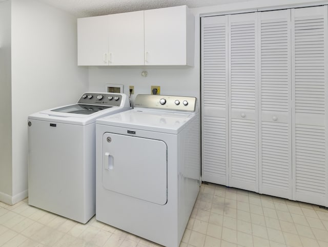 laundry area featuring washing machine and dryer, cabinets, and a textured ceiling