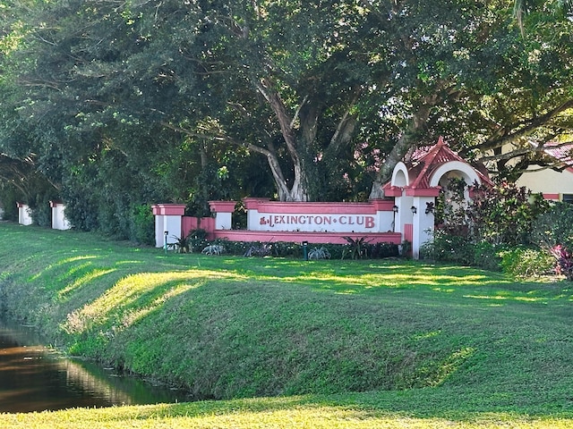 community / neighborhood sign with a water view and a lawn