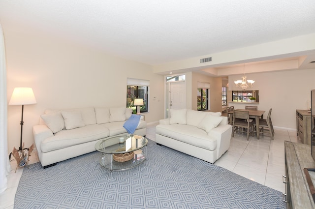 tiled living room featuring a chandelier and a tray ceiling