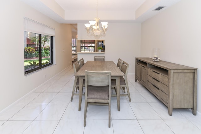 tiled dining room with a tray ceiling and a notable chandelier