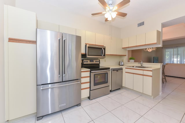 kitchen featuring ceiling fan, sink, cream cabinetry, light tile patterned floors, and appliances with stainless steel finishes