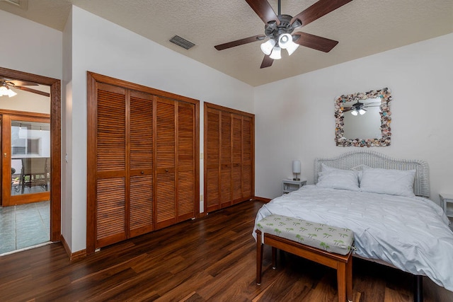 bedroom featuring a textured ceiling, multiple closets, ceiling fan, and dark hardwood / wood-style floors