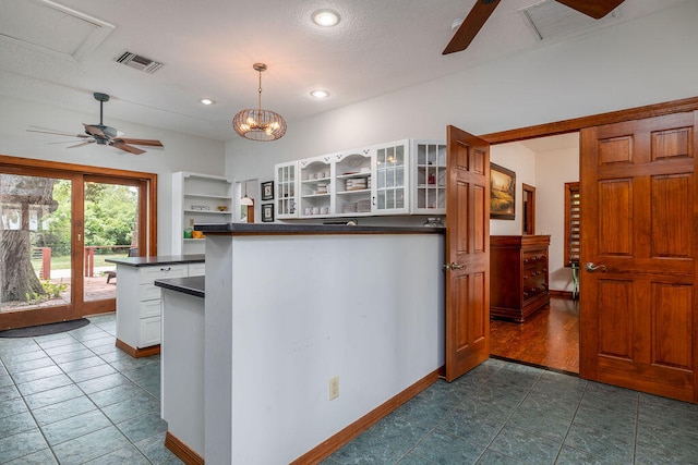 kitchen featuring white cabinets, pendant lighting, and ceiling fan with notable chandelier