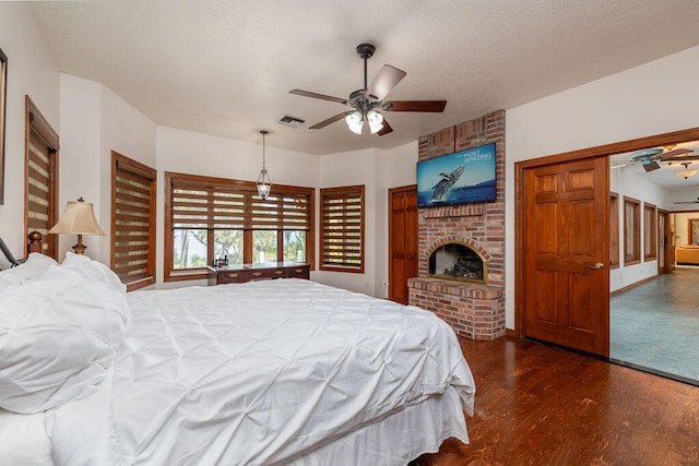 bedroom featuring dark hardwood / wood-style flooring, a textured ceiling, ceiling fan, a fireplace, and a closet