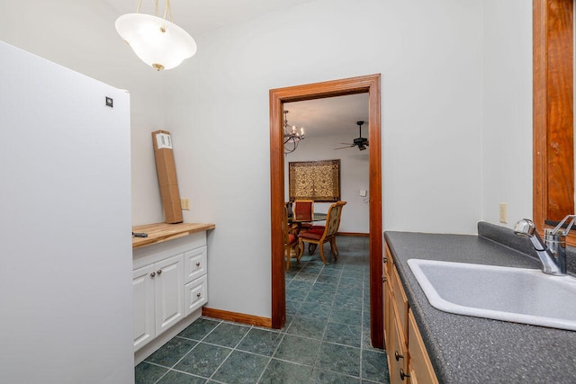 interior space with ceiling fan with notable chandelier, white cabinetry, hanging light fixtures, and sink