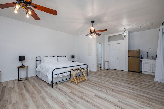 bedroom with stainless steel fridge, light wood-type flooring, ensuite bathroom, ceiling fan, and a closet