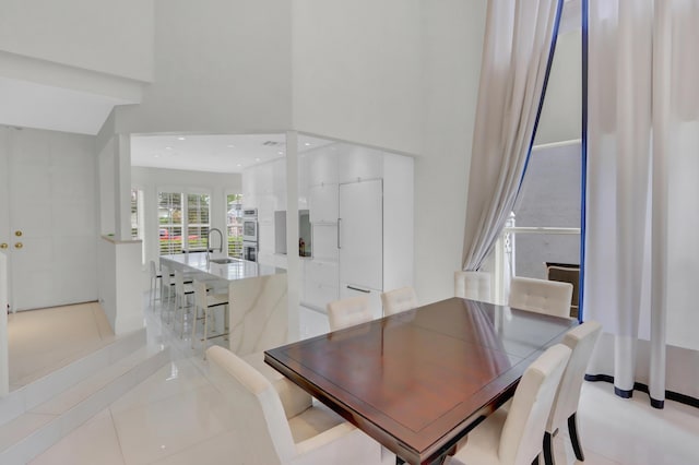 tiled dining room featuring sink and a high ceiling