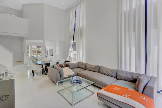 living room with a towering ceiling and light tile patterned flooring