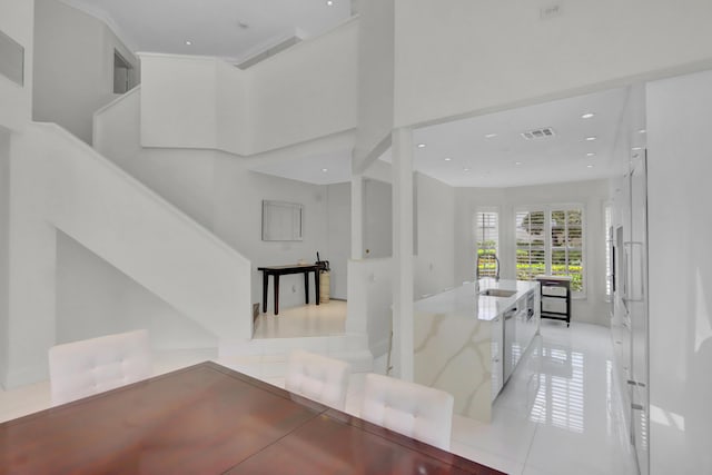 hallway with crown molding, sink, a high ceiling, and light tile patterned floors