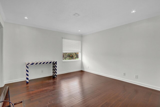 empty room with ornamental molding and dark wood-type flooring