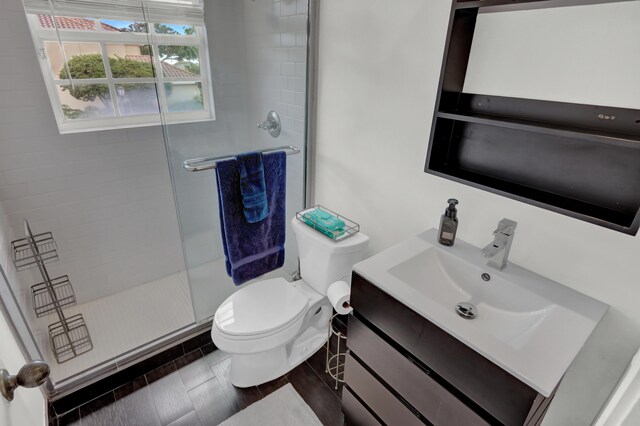 bathroom featuring vanity, toilet, and a shower with shower door