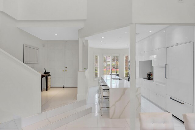 kitchen featuring white cabinets, a kitchen bar, and light tile patterned floors