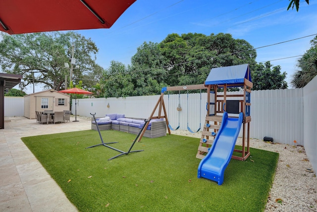 view of play area featuring a lawn, a storage unit, an outdoor living space, and a patio